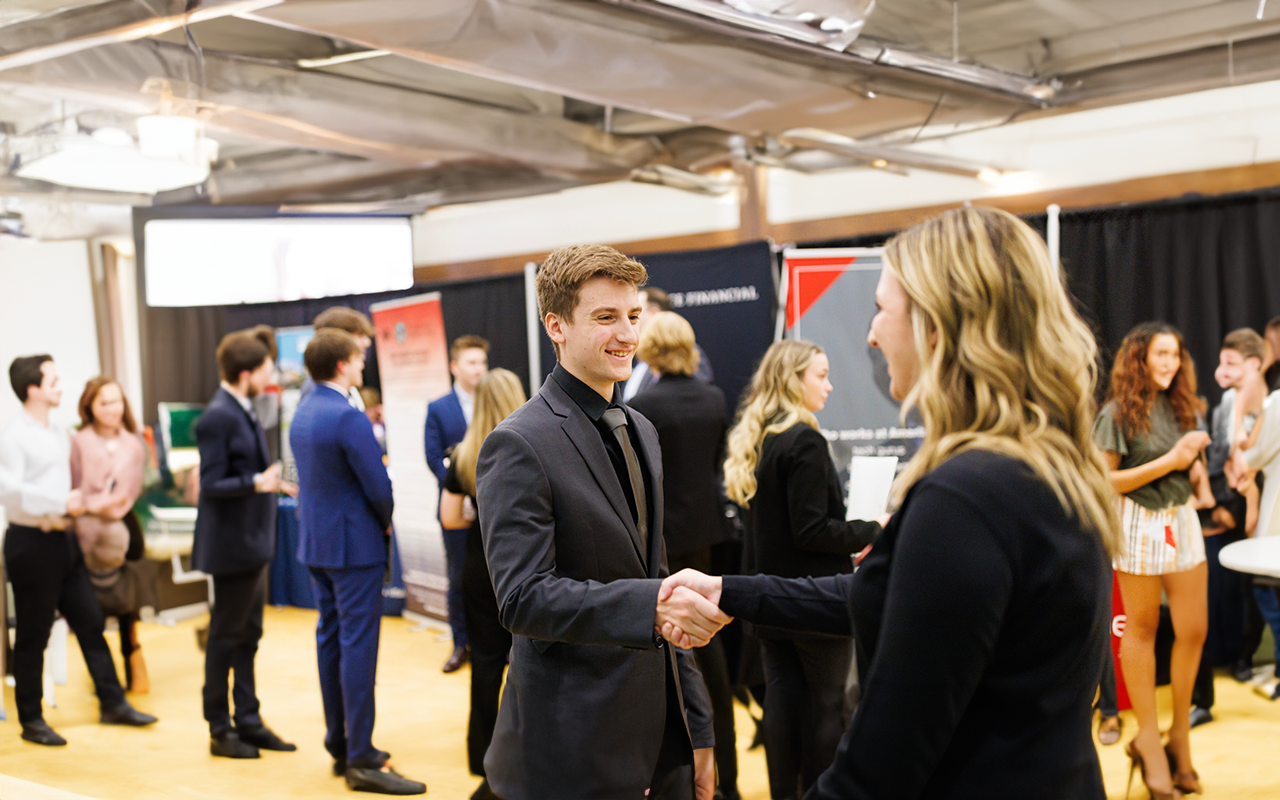 student shaking hands with a recruiter at a career fair