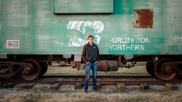 Kolton Jueneman smiling in front of train.