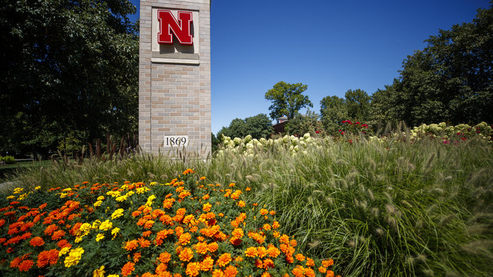 Nebraska N on pillar behind flowers on East Campus gateway