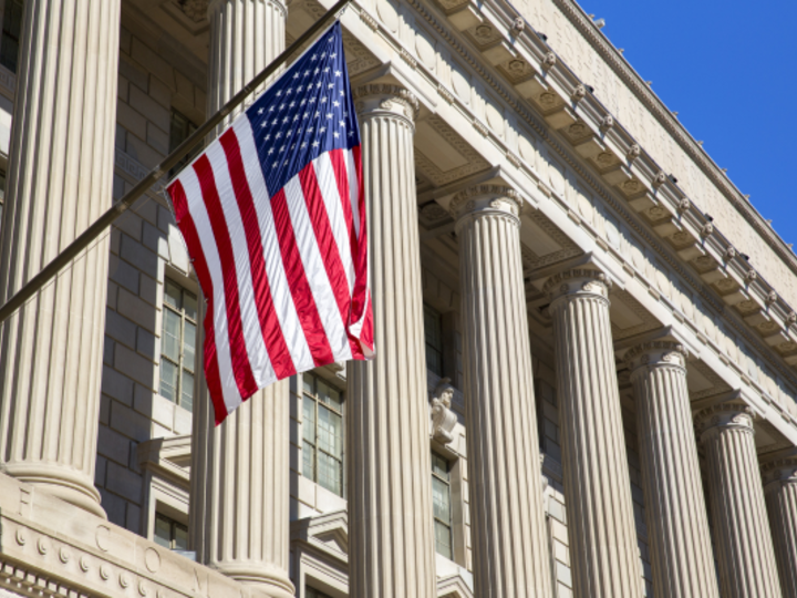 American flag hanging in front of federal building collumns