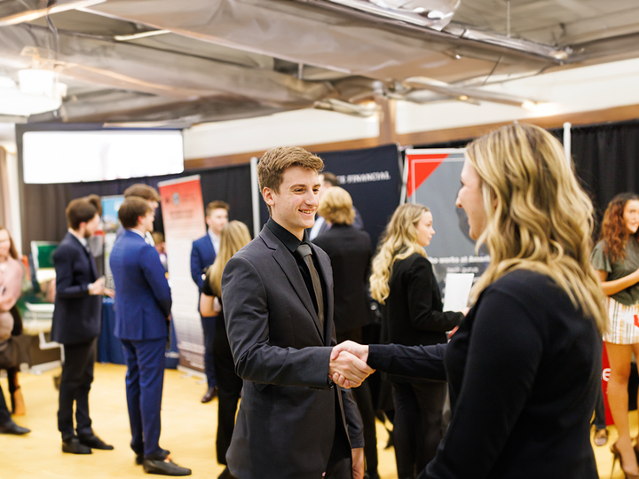 student shaking hands with a recruiter at a career fair