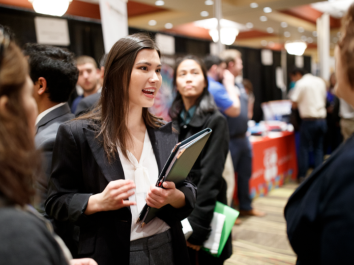 female in professional attire talks to recruiter at career fair