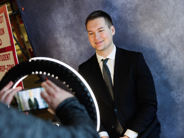 Male student in suit in front of ring light taking headshot photo