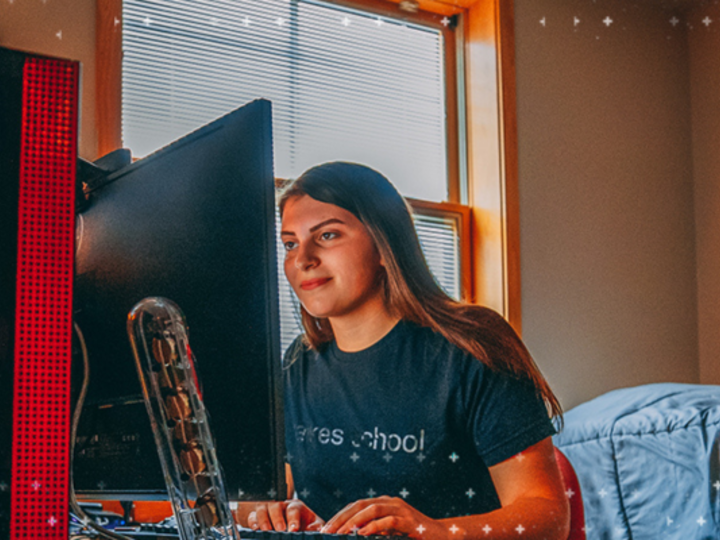 Student in dorm room sits in front of computer screen