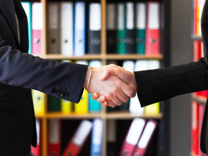 handshake between 2 people in suits in front of bookcase