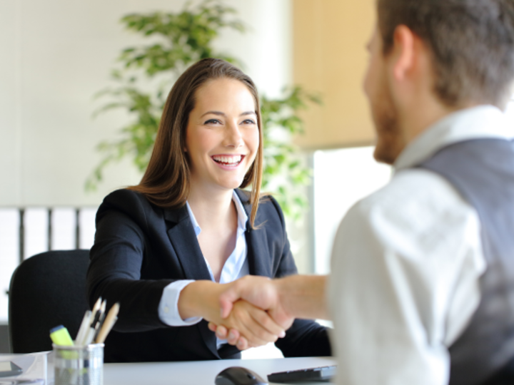 female in professional attire shakes hands with interviewer