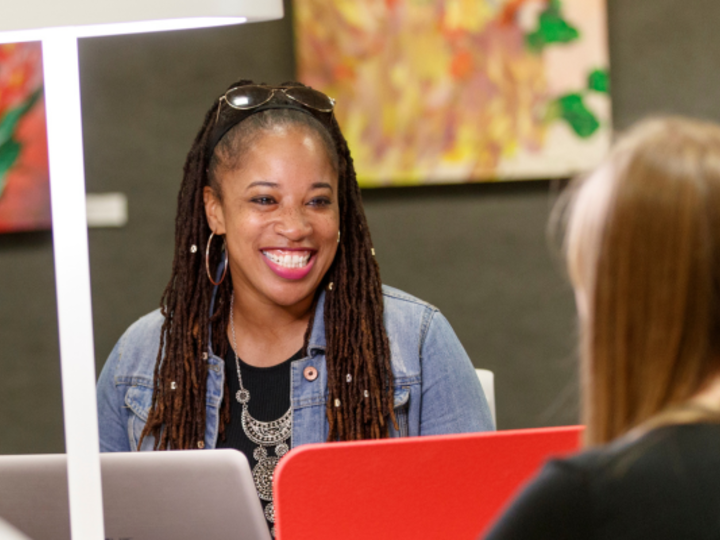 Text: Pursuing Graduate School.  Female black student smiling and looking at another person