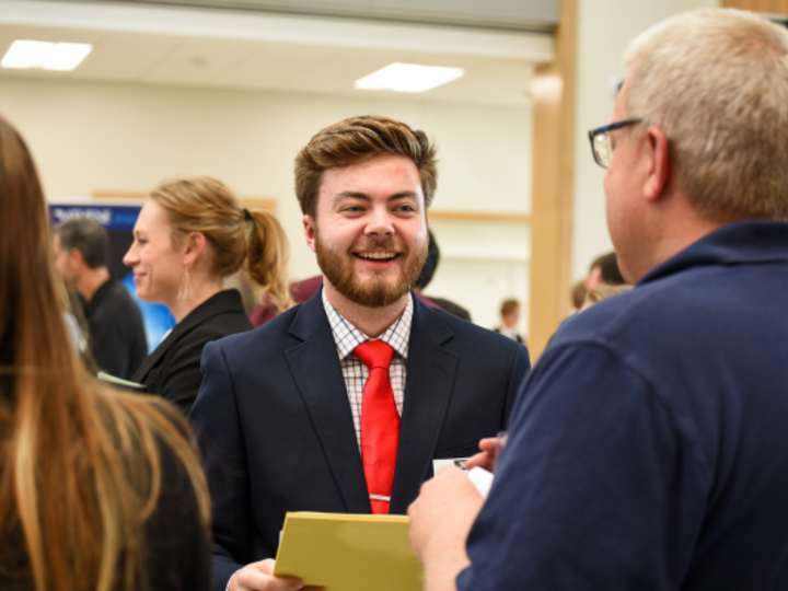 male in professional attire smiles at recruiter at Actuarial Science Career Fair