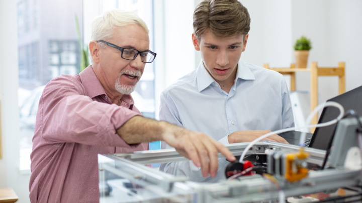 Male employer shows machine to younger student